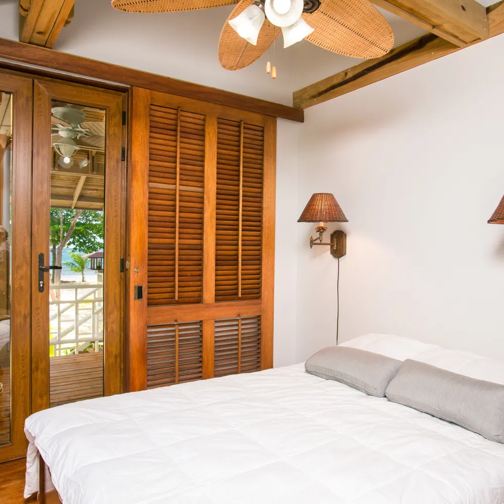 A simple double bedroom with white linen and wooden shutters