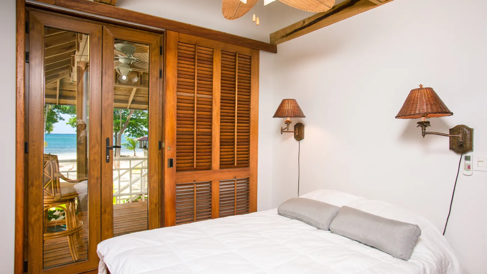 A simple double bedroom with white linen and wooden shutters